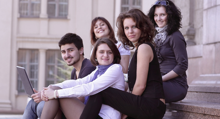portrait of a group of students sitting in front of the University