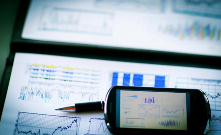 Phone on documents with charts and graphs