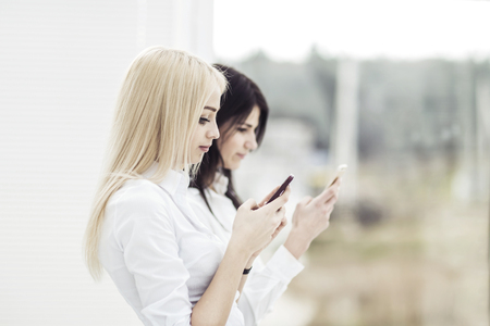 young women employees of the company exchange information on a smartphoneの写真素材