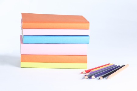 colored pencils and stack of books on white background. photo with copy spaceの写真素材