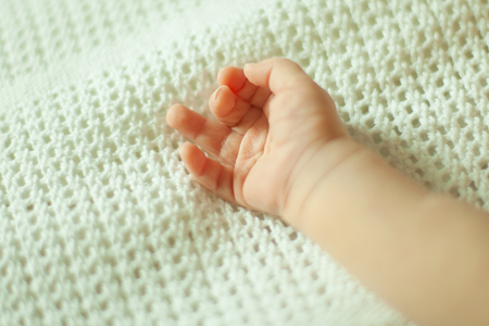 hand of a newborn baby on a white blanketの写真素材