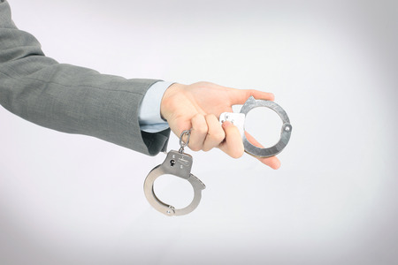 The hand holding the handcuffs.