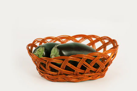 two ripe eggplant in a wicker basket.isolated on white.photo with copy spaceの写真素材