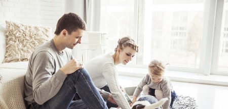 happy family playing with a pet dog in the spacious living roomの写真素材