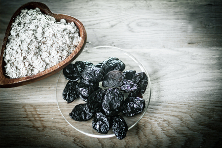 prunes in a bowl and cereal on a wooden tableの写真素材