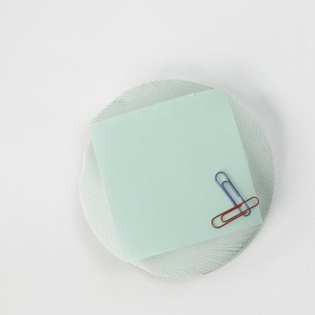 Blank sheet for notes and paper clip isolated on white background