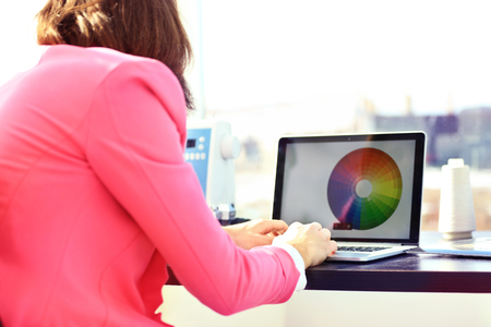 Cropped image of photo editor with color swatches working on laptop at deskの写真素材