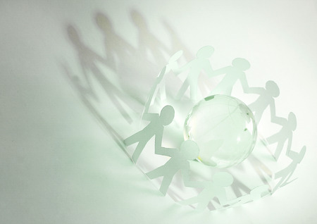 glass globe and a family of paper men on a green backgroundの写真素材