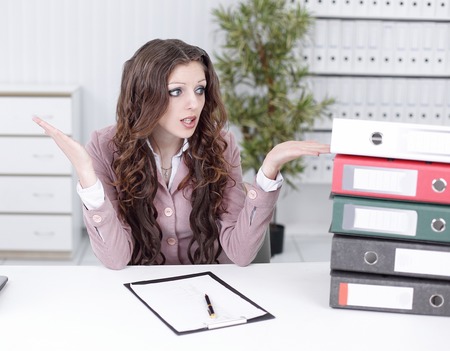 confused business woman looking at a big stack of documentsの写真素材