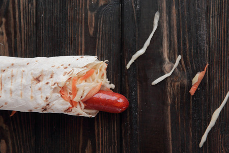 sausages and salad wrapped in lavash on wooden background.photoの写真素材