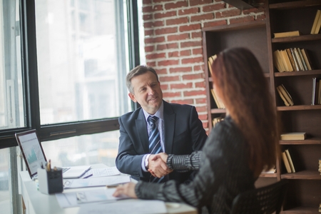 handshake of business partners sitting at their Deskの写真素材