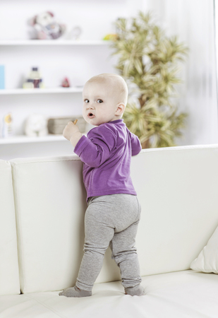 portrait of a happy one year old baby girl on a background of bright childrens roomの写真素材