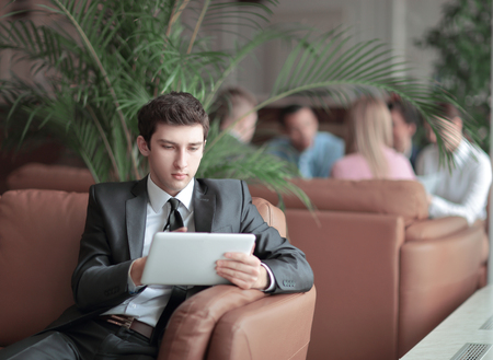 close-up of a young businessman using a digital tablet sitting in the lobby of the Bankの写真素材