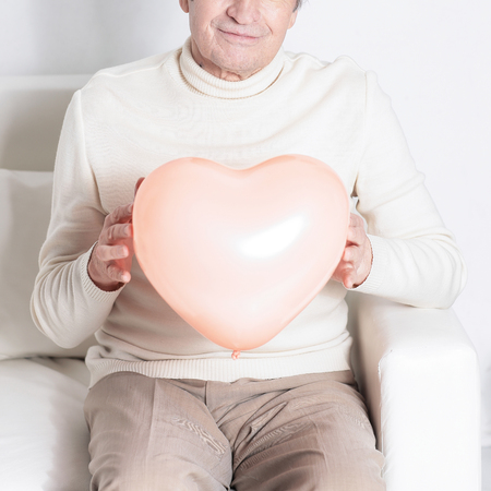 elderly man showing a big heart.isolated on whiteの写真素材