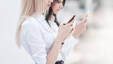 young women employees of the company exchange information on a smartphoneの写真素材