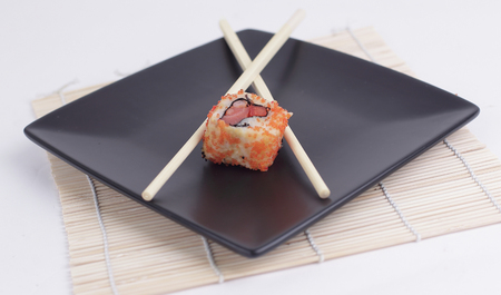 close-up of sushi and chopsticks on a black plate .isolated on a light background.の写真素材