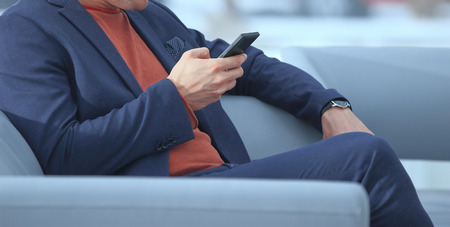 close up.businessman using mobile phone sitting in the lobby of the hotelの写真素材