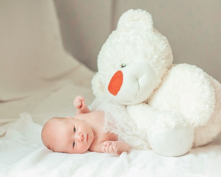 portrait of a newborn baby with a soft toy in the parents  bedの写真素材