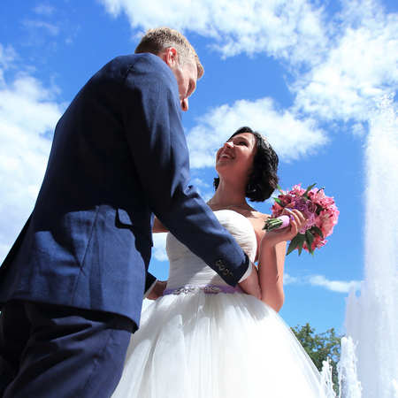 closeup of a loving bride and groom standing next to the fountainの写真素材