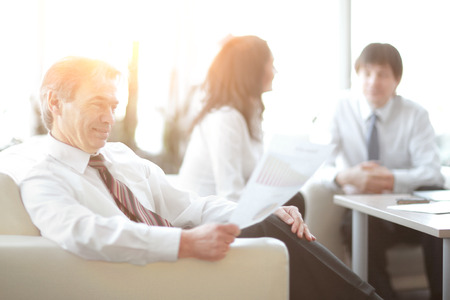 businessman pondering a document sitting in a modern officeの写真素材