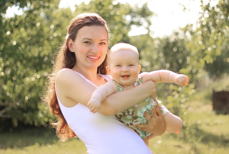 smiling mother playing with her little daughter in summer Parkの写真素材