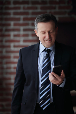 senior businessman reading text message on smartphone.の写真素材