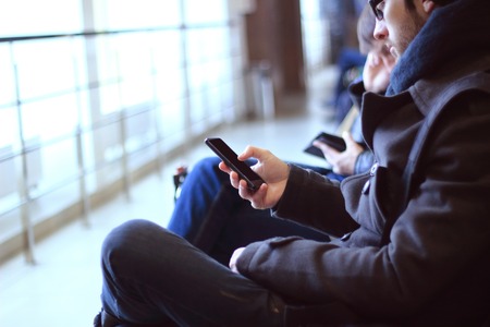 close up.modern man with smartphone sitting in airport buildingの写真素材