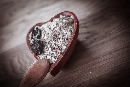 muesli with prunes in a wooden bowl on the tableの写真素材