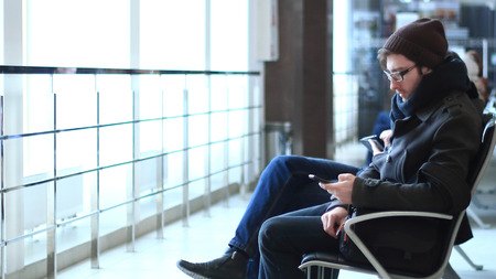 close up.modern man with smartphone sitting in the airport waiting room