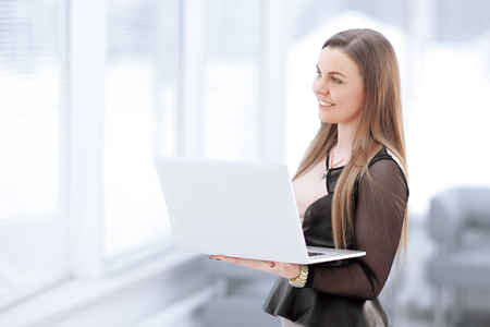 young business woman with laptop standing in office lobbyの写真素材