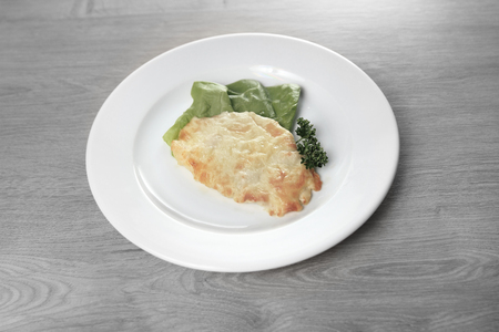 chicken with cheese on white plate on wooden backgroundの写真素材