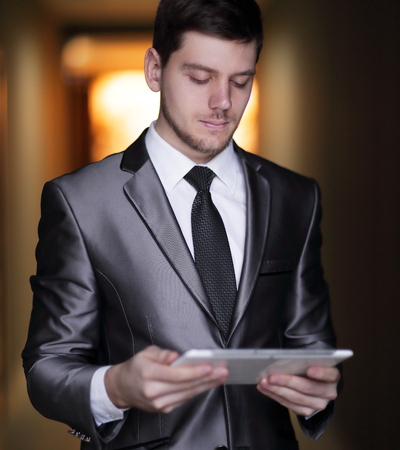 close up. portrait of elegant businessman with digital tablet on office backgroundの写真素材