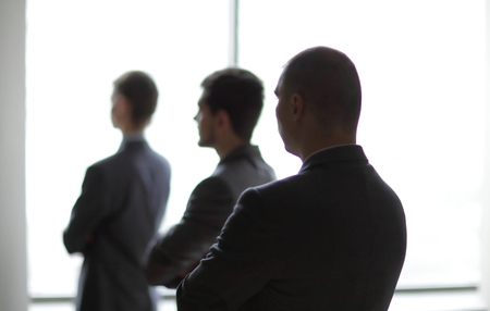 back view three employees as they look out on a large window overlooking the cityの写真素材