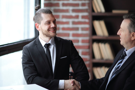 friendly handshake of business partners sitting at a Deskの写真素材