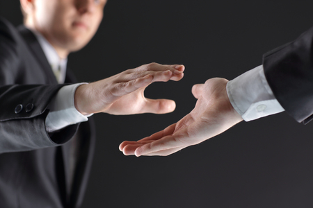 two businessmen are holding out their hands for a handshake.の写真素材