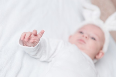 baby lying on the bed and pointing up.