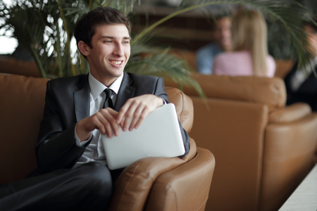 close-up of a young businessman using a digital tablet sitting in the lobby of the Bankの写真素材