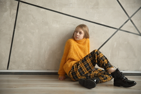 cute teen girl sitting near the wall.の写真素材