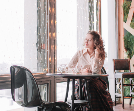cute young woman sitting at a table in a cafeの写真素材