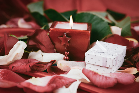 box with a gift and candle on the background of rose petals.の写真素材