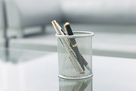 pencil stand and glasses on the glass Desk in the officeの写真素材