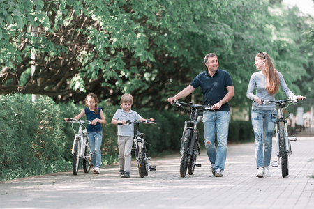 modern family with their bikes walk through the city Parkの写真素材