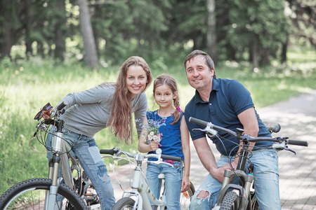 portrait of a happy family with a little daughter on a bike rideの写真素材