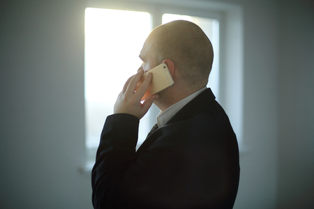 close up. businessman talking on smartphone, on blurred background of office window.の写真素材