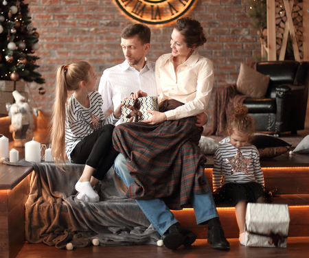 parents with their young children sitting in the living room decorated for Christmasの写真素材