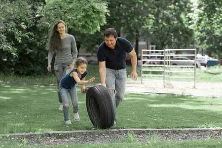 parents playing with her daughter on the Playground near the house