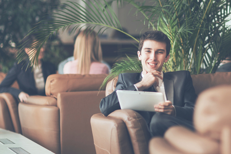 Entrepreneur-novice with a digital tablet sitting on the couch in the lobby of a modern officeの写真素材