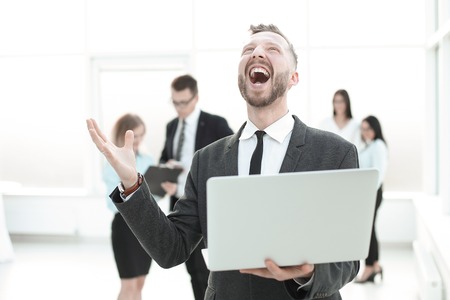 very happy businessman with laptop on light office background .の写真素材