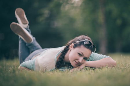 cute young woman lying on green grass.の写真素材