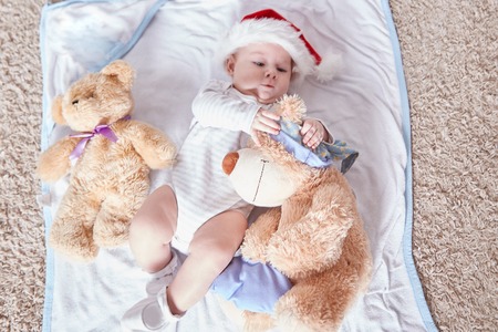 happy baby in Santas hat with soft toys